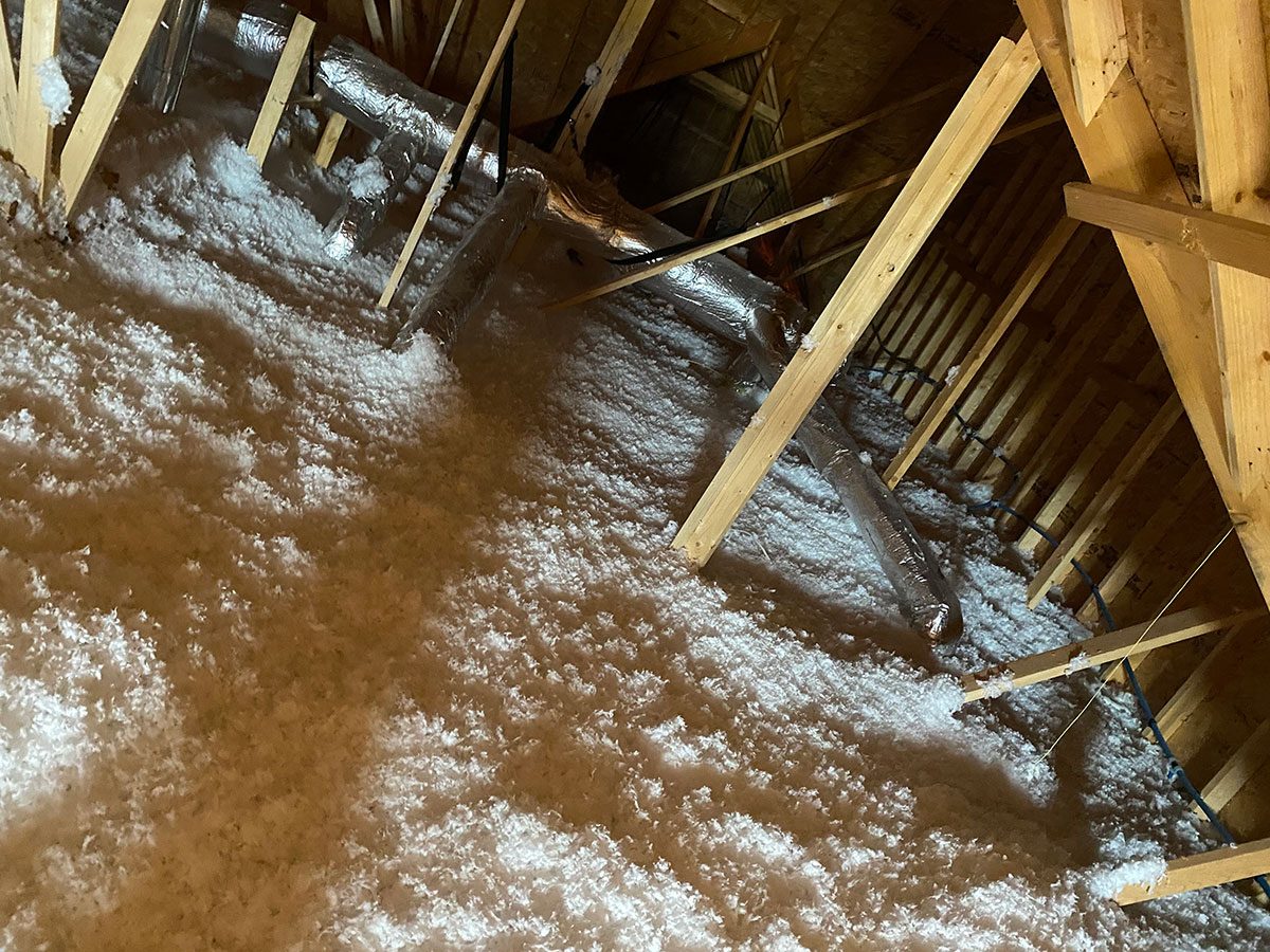Blown-in fiberglass attic insulation around HVAC ductwork